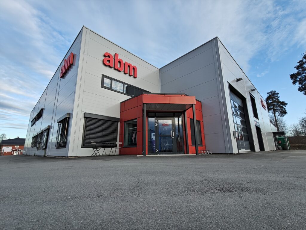 Røde fasadebokstaver som viser logo montert på en fasade.