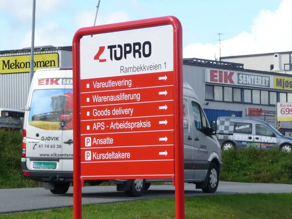 Rødt informasjonsskilt for Topro på Rambekkveien med retninger og parkering